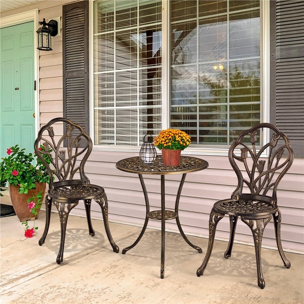 Bistro-Set aus Metall für den Außenbereich, bestehend aus einem runden Tisch und zwei Stühlen mit floralem Design auf einer hellen Terrasse.