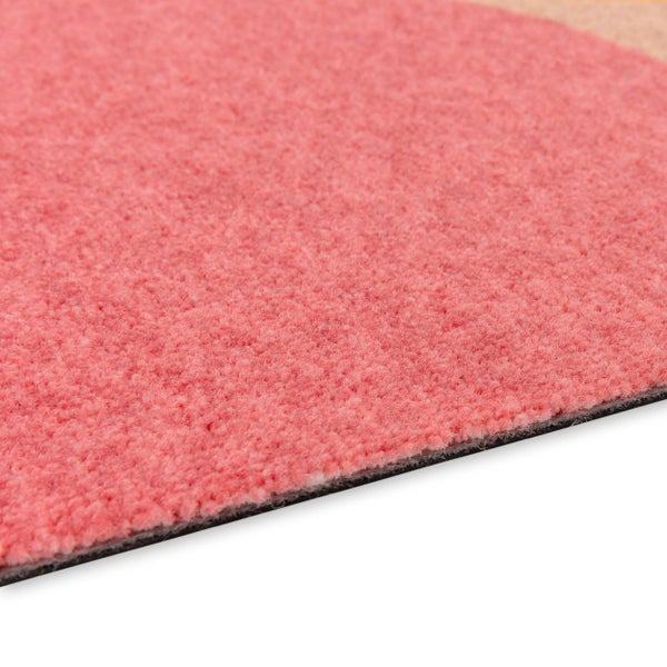 Nahaufnahme eines rosa kurzflorigen Teppichs mit weicher Textur und dünnem schwarzen Rücken.