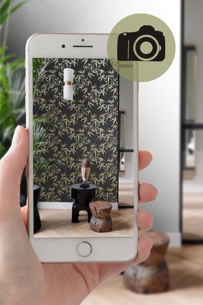 Smartphone zeigt ein Wohnzimmer mit schwarzer Bambus-Tapete