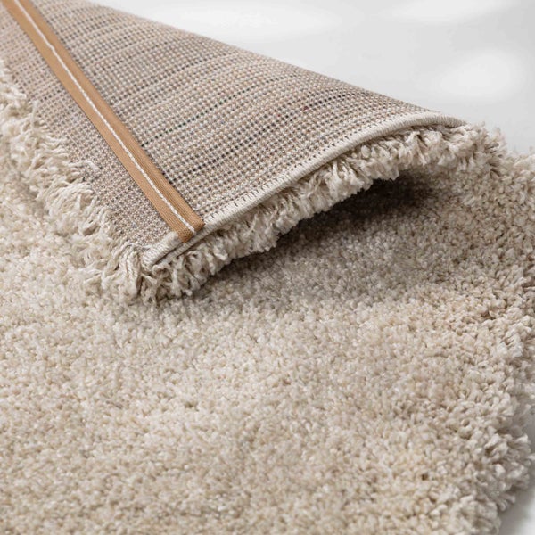 Hochflor-Teppich mit weicher Struktur, Detailansicht der gewebten Rückseite und verstärkten Kanten.