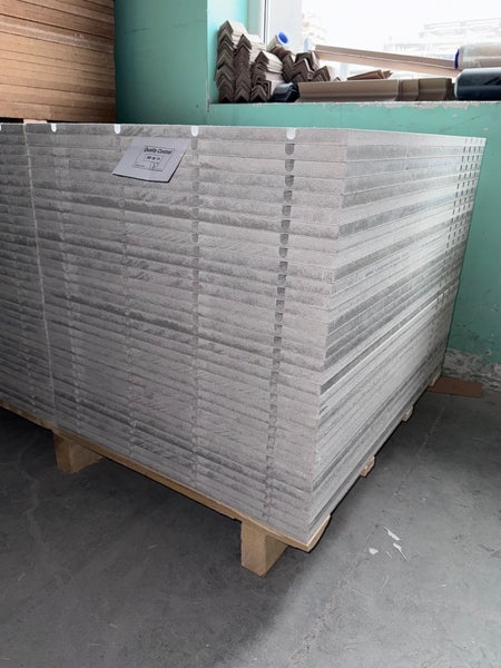 Stapel graue zementgebundene Spanplatten auf einer Holzpalette im Lager.