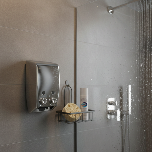 Doppelter Seifenspender aus Chrom an einer gefliesten Wand in einer Dusche neben einem Duschkorb mit Schwamm.