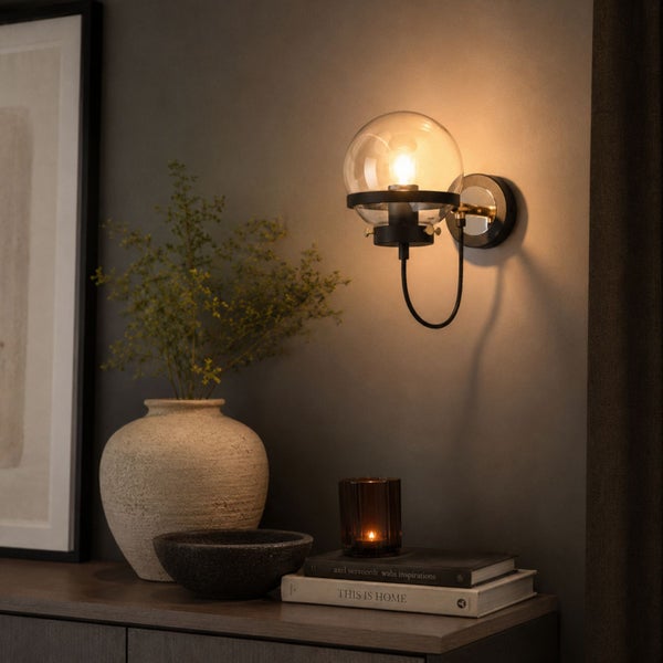 Moderne Wandleuchte mit Glaskugel auf einer Kommode mit Dekoration in einem Wohnraum.