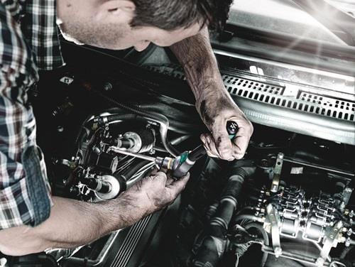 Ein Mechaniker arbeitet an einem Automotor mit einem Schraubenschlüssel.