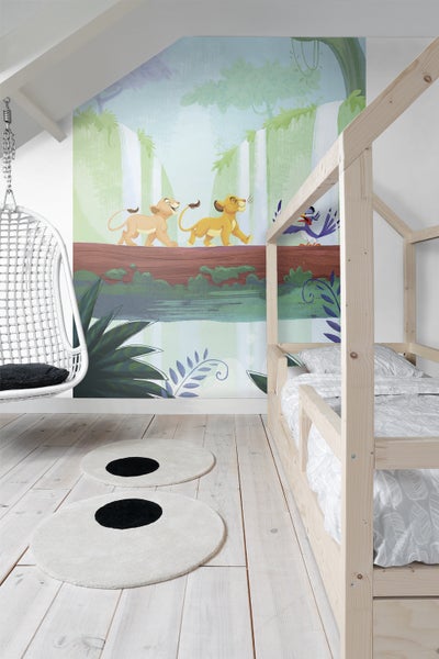 Kinderzimmer mit Dschungeltapete, Holzbett, Hängesessel und runden Teppichen