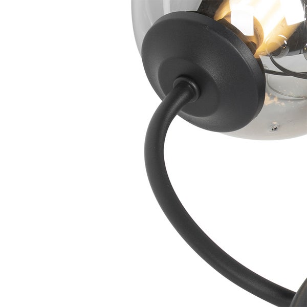 Nahaufnahme einer schwarzen Wandleuchte mit einem transparenten Glasschirm.