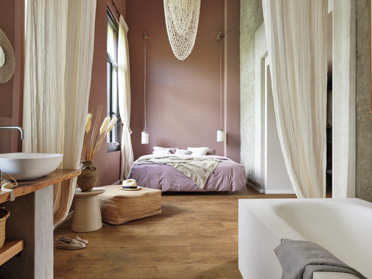 Großzügiges Schlafzimmer mit integriertem Badezimmer, Holzoptik Boden, Doppelbett und freistehendem Waschbecken in modernem, wohnlichem Stil.