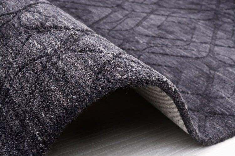 Strukturierter Teppich mit geometrischem Muster, Kante leicht aufgerollt, Ansicht der Textur und Teppichrückseite.