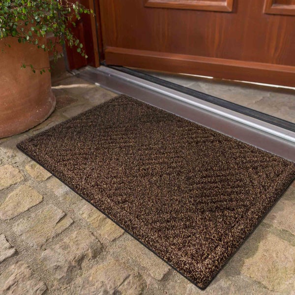 Fußmatte aus Textil vor einer Haustür auf Steinfliesen