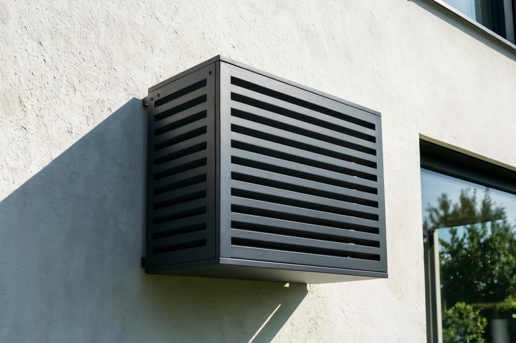Eine an einer Wand montierte Klimaanlagenverkleidung mit horizontalen Lamellen.