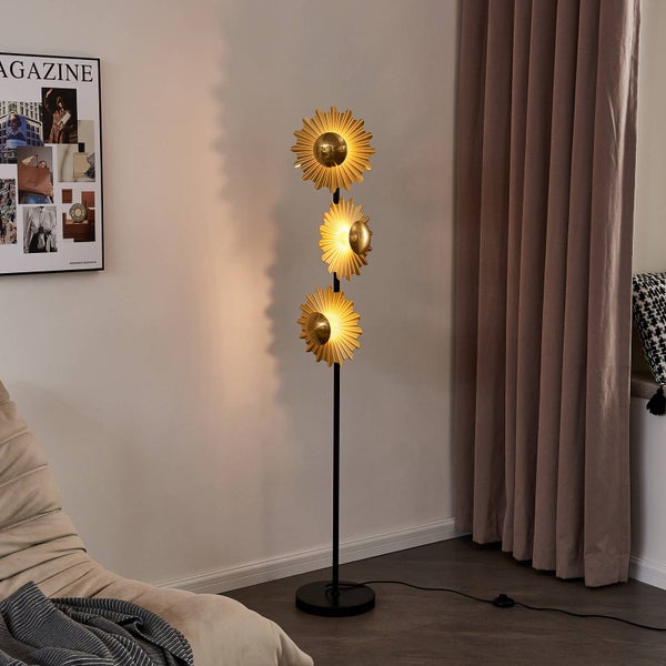 Stehlampe mit drei goldenen Lampenschirmen in Form von stilisierten Sonnenblumen in einem Wohnzimmer.
