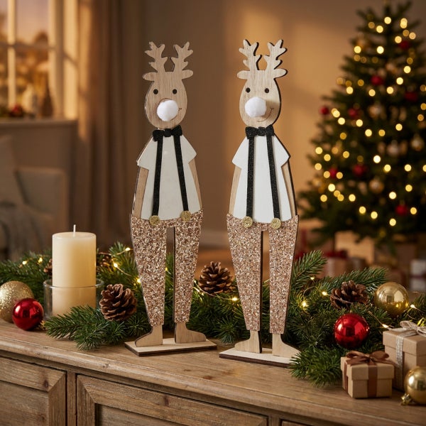 Zwei dekorative Holzrentier Figuren mit Glitzerhosen und flauschiger Nase als weihnachtliche Tischdekoration auf einem festlichen Sideboard.