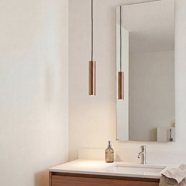 Modernes Badezimmer mit Waschtisch, zwei zylindrischen Pendelleuchten, Spiegel und Waschbeckenarmatur in einer hellen und wohnlichen Umgebung.
