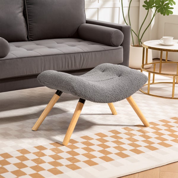 Szene mit grauem Fußhocker mit Holzbeinen vor einem grauen Sofa