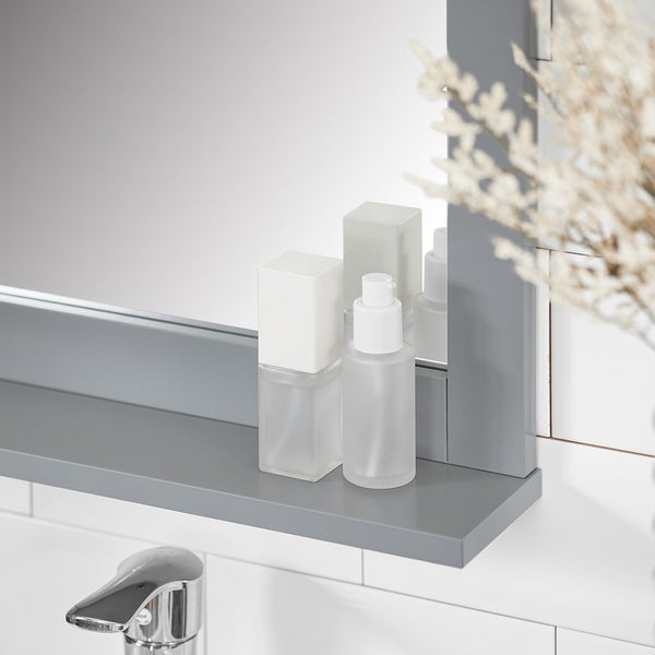 Detailansicht eines Badezimmerspiegels mit Ablage und zwei Kosmetikflaschen