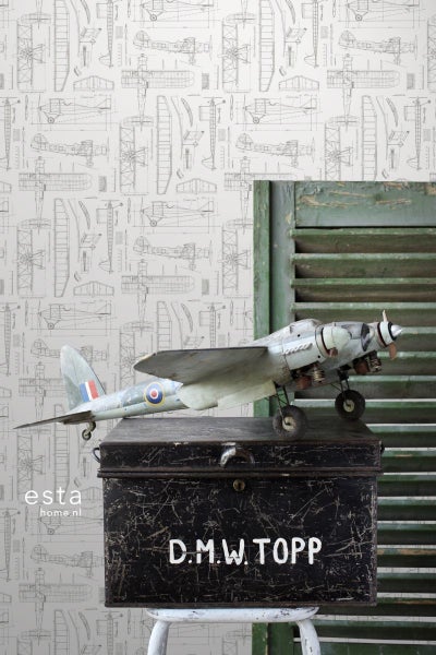 Szene mit Flugzeugmodell auf einem Koffer vor einer Tapete mit Flugzeugmotiven