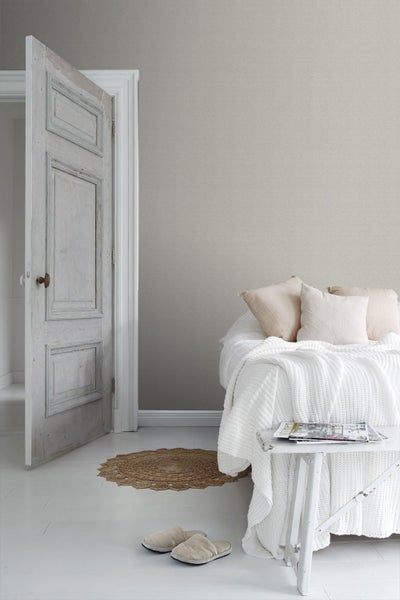 Helles Schlafzimmer mit Bett, Nachttisch, Teppich und geöffneter Tür