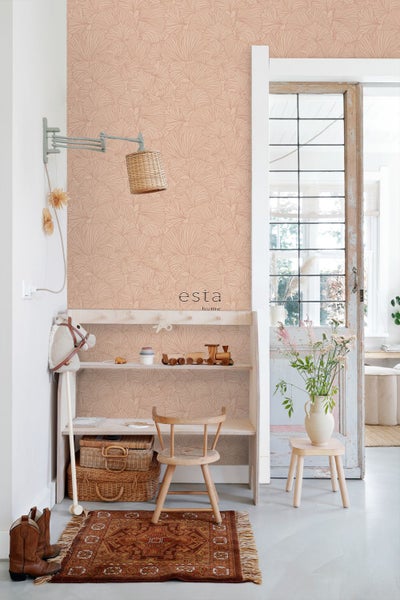 Eine Kinderecke mit Esta Home Vliestapete mit Ginkgo Muster in einem hellen Kinderzimmer mit Holzmöbeln und Dekoration.