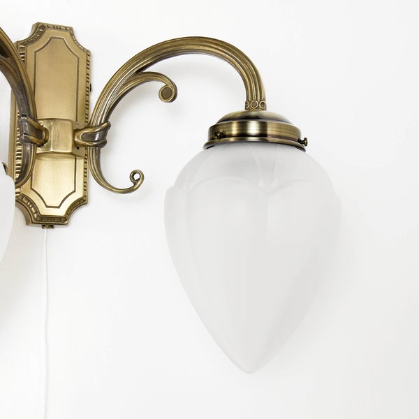 Klassische Wandleuchte in Antikoptik mit geschwungenem Metallarm und einem tulpenfoermigen, satinierten Glasschirm.