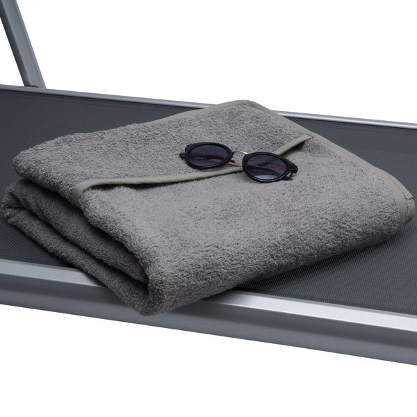 Graues Frotteehandtuch gefaltet mit Sonnenbrille auf einer Liege