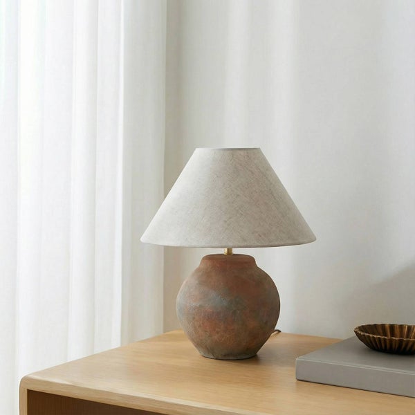 Tischleuchte mit Stoffschirm und Keramikfuß auf einem Tisch