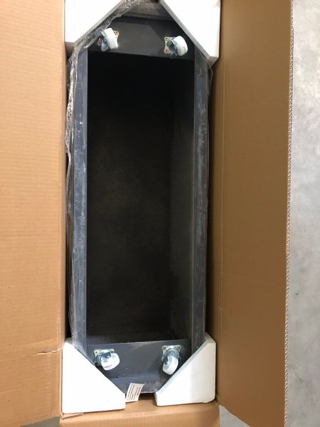 Dunkelgrauer rechteckiger Pflanzkübel mit Rollen in einer Kartonverpackung mit Schaumstoff-Eckschutz.
