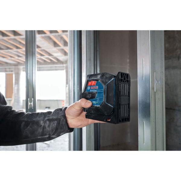 Eine Hand hält einen Bosch Professional Kreuzlinienlaser gegen ein Metallständerprofil auf einer Baustelle zur präzisen Ausrichtung.