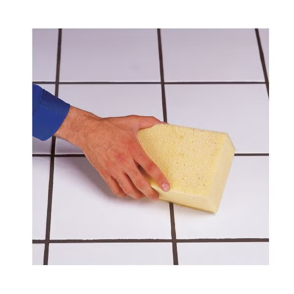 Eine Hand reinigt eine geflieste Wand mit einem Schwamm