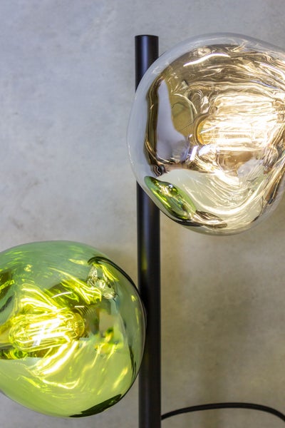 Moderne Stehleuchte mit zwei organisch geformten Glasschirmen in Grün und Klar sowie Filament-Leuchtmitteln an einer schwarzen Stange.