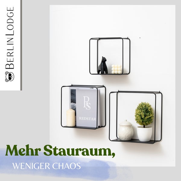 Berlin Lodge Logo neben drei quadratischen Wandregalen aus schwarzem Metall, dekoriert mit Figuren, Büchern und Pflanzen.
