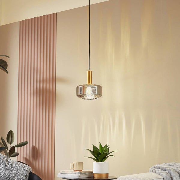 Moderne Pendelleuchte mit geriffeltem Glasschirm und goldfarbener Fassung in einem hellen Wohnzimmer mit Wandpaneel.