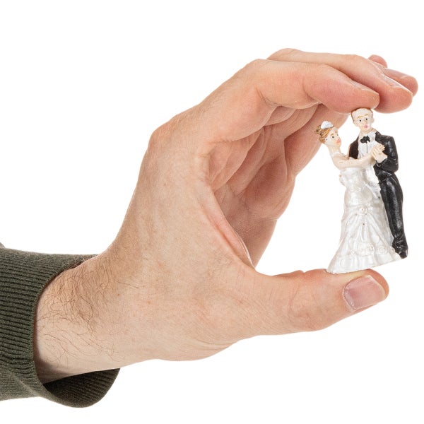 Eine Hand hält eine kleine Figur eines Brautpaares.