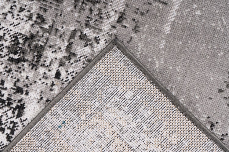 Teppich mit abstraktem Muster, umgeschlagener Ecke, gekettelter Kante und gewebter Rückseite.