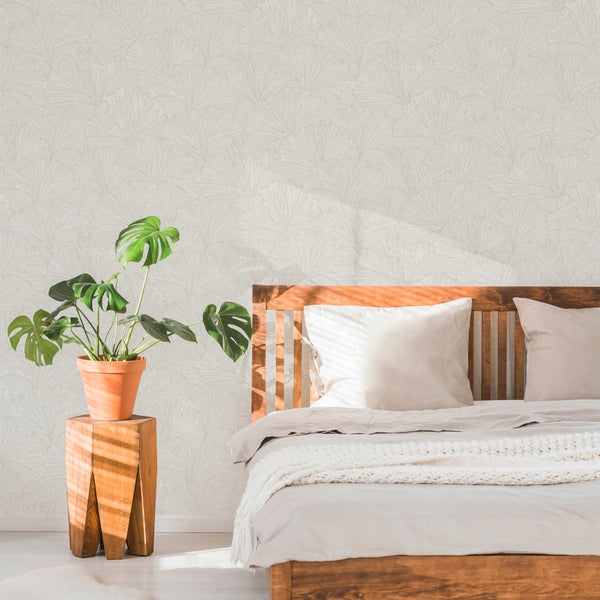 Schlafzimmer mit Bett, Pflanze und Tapete mit Blättermuster