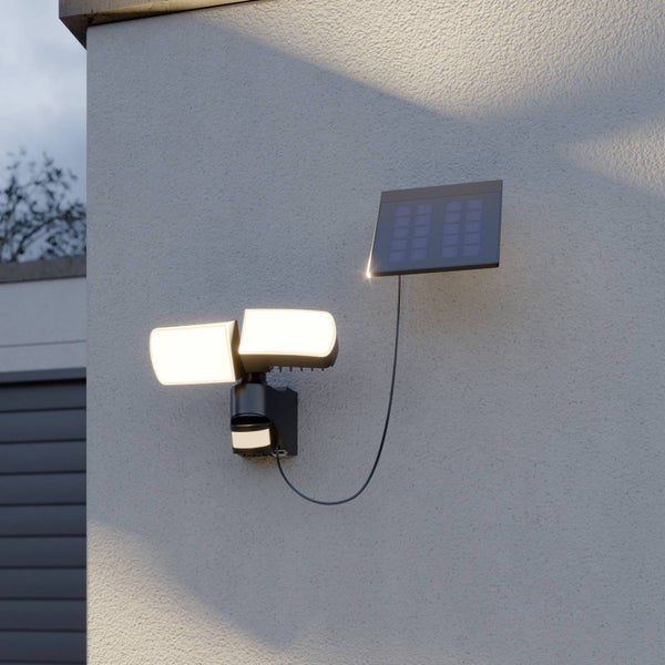 Solar-LED-Außenstrahler mit Bewegungsmelder, zwei verstellbaren Leuchtenköpfen und separatem Solarpanel an einer Hauswand.