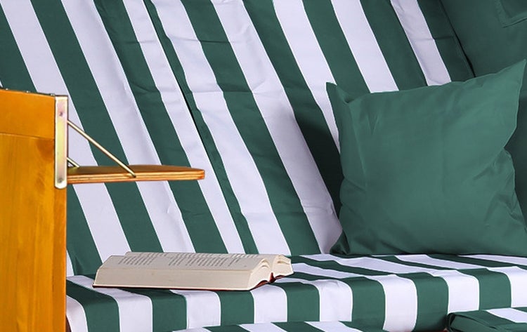 Zierstrauch mit grünen und rötlichen Blättern im Gartenbeet.