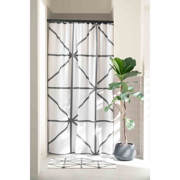 Badezimmer mit Duschvorhang mit geometrischem Muster, passendem Teppich und Topfpflanze