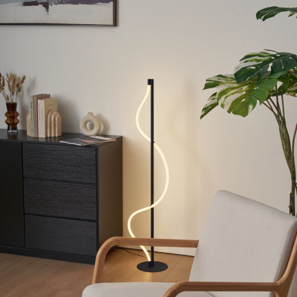 Moderne Stehlampe mit geschwungenem Lichtelement in einem stilvollen Wohnzimmer.