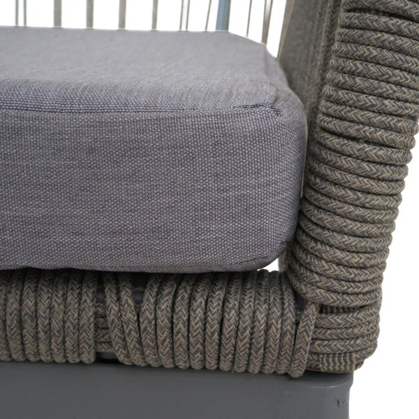 Detailansicht eines Gartenstuhls mit grauem Stoffkissen und geflochtenen Elementen