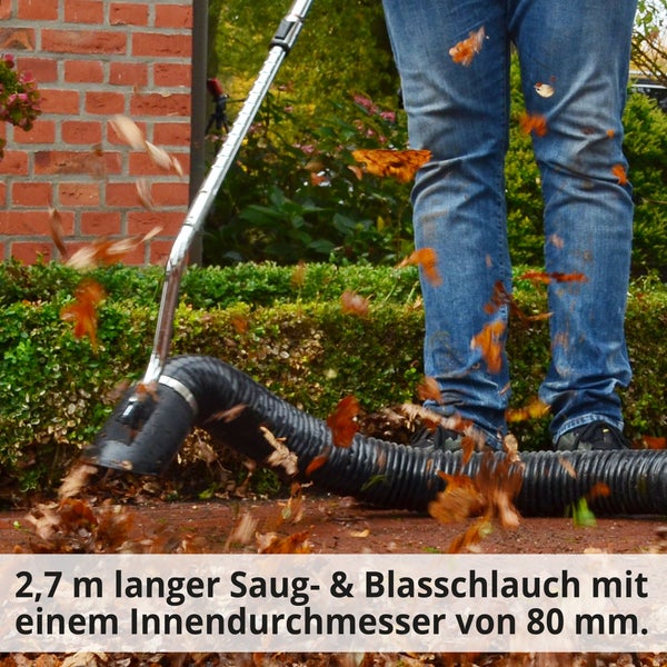 Gartenszene mit Person, die einen Laubsauger benutzt, um Blätter aufzusammeln