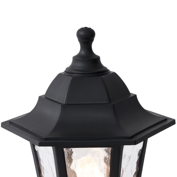 Detailansicht des schwarzen Daches und der dekorativen Spitze einer traditionellen Außenleuchte mit strukturiertem Glas.