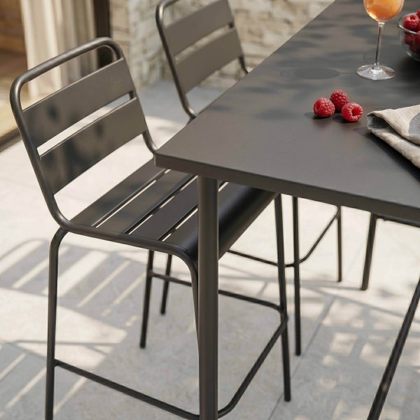 Garten-Barset aus Metall mit hohem Tisch und Barstühlen mit Rückenlehne auf einer hellen Terrasse.