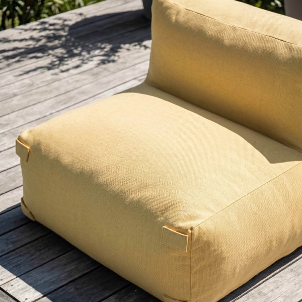 Gelber Outdoor Loungesessel aus strukturiertem Stoff auf einer Holzterrasse.
