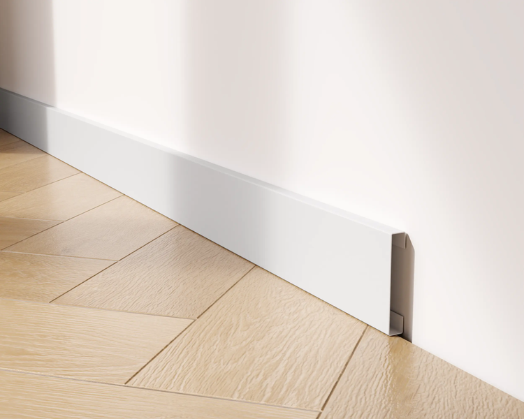 Detailaufnahme einer weißen Sockelleiste an einer Wand mit Holzboden.