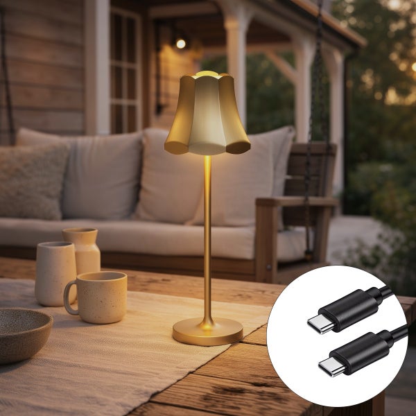 Goldfarbene Akku-LED-Tischleuchte mit blumenförmigem Schirm auf einem Holzgartentisch, Terrasse mit Sitzbank im Hintergrund, inklusive USB-C-Kabel.