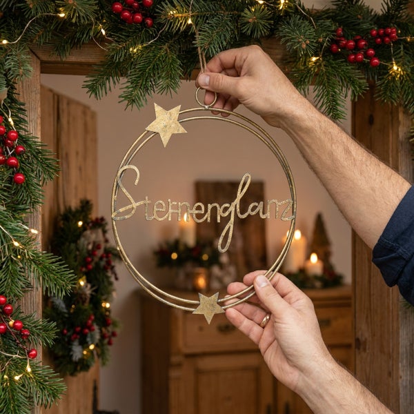 Dekorativer Metallring mit Sternen und Schriftzug Sternenglanz zum Aufhängen für eine weihnachtliche Dekoration.