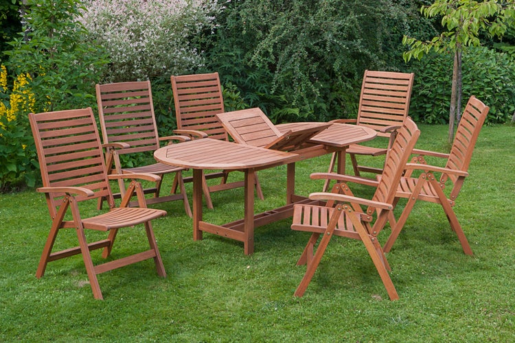 Gartenszene mit ovalem Holztisch und sechs Holzstühlen auf einer Rasenfläche