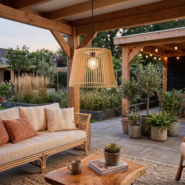 Moderne Hängelampe aus Holz mit Lamellenoptik in einer überdachten Terrasse mit Rattanmöbeln und Pflanzen.