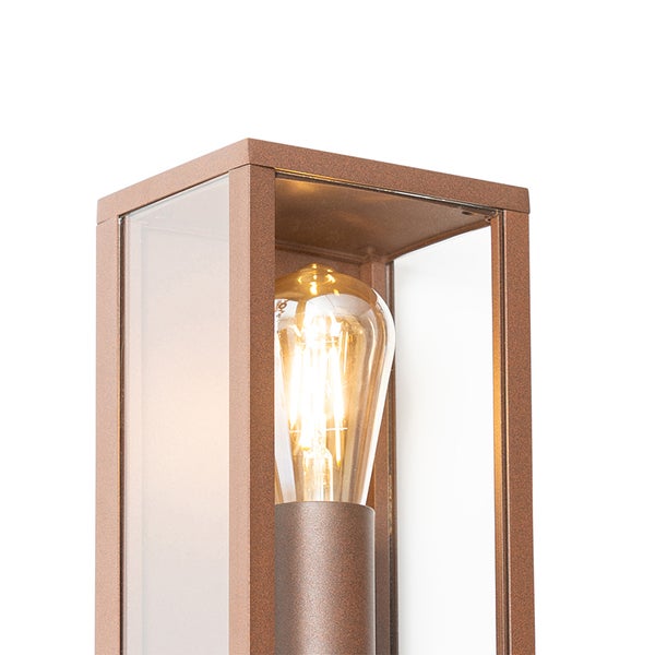 Außenwandleuchte in Laternenform aus rostfarbenem Metall mit Glaseinsätzen und leuchtendem LED-Filament-Leuchtmittel.