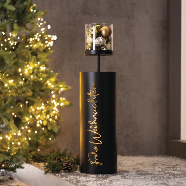 Zylindrische Weihnachtsdekoration aus Metall mit beleuchtetem Schriftzug Frohe Weihnachten und einem gläsernen Aufsatz mit Weihnachtskugeln